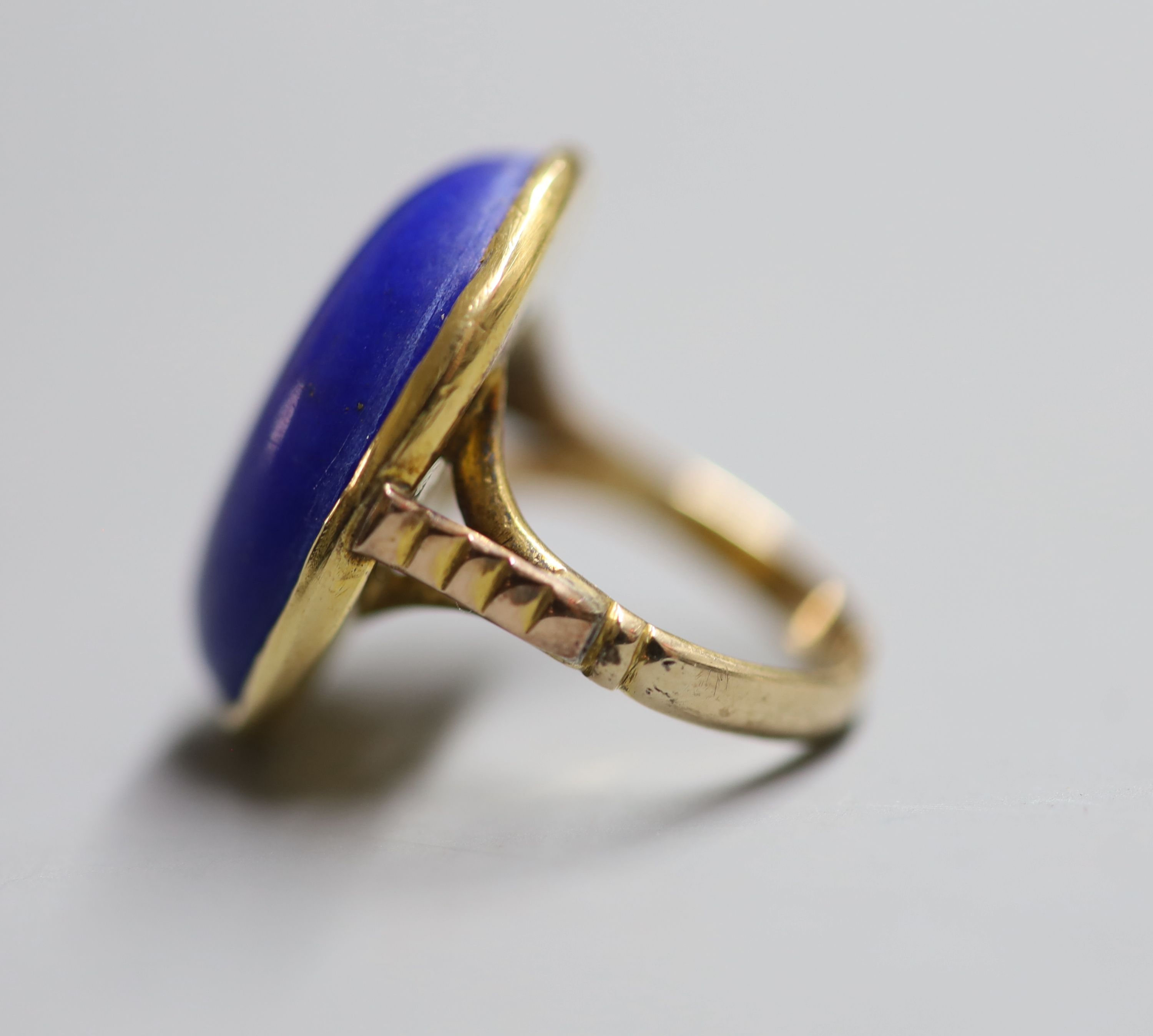 An early 20th century yellow metal and cabochon lapis lazuli set dress ring, size J, gross 8.4 grams (a.f.),